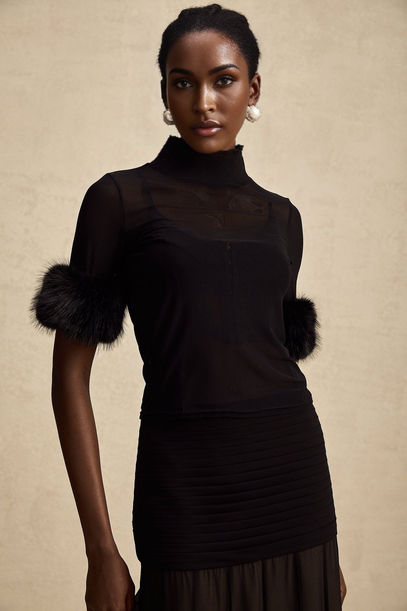 Woman wearing black sleeveless top with faux fur bodice and sheer tulle overlay