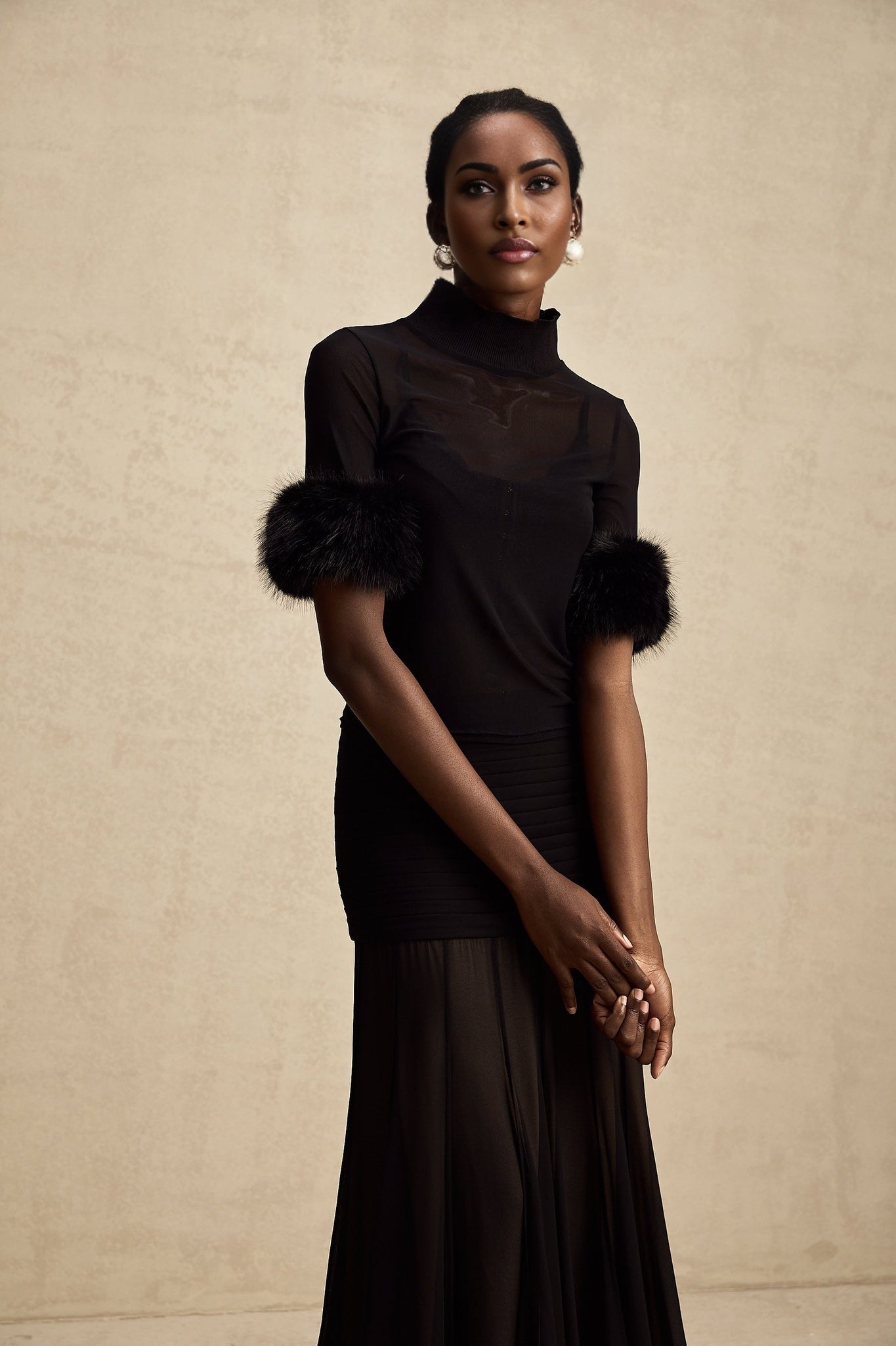 Woman wearing black sleeveless top with faux fur trim and sheer tulle overlay
