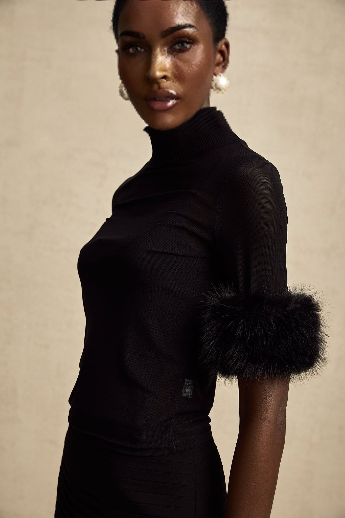 Woman wearing black sleeveless top with faux fur trim and tulle overlay