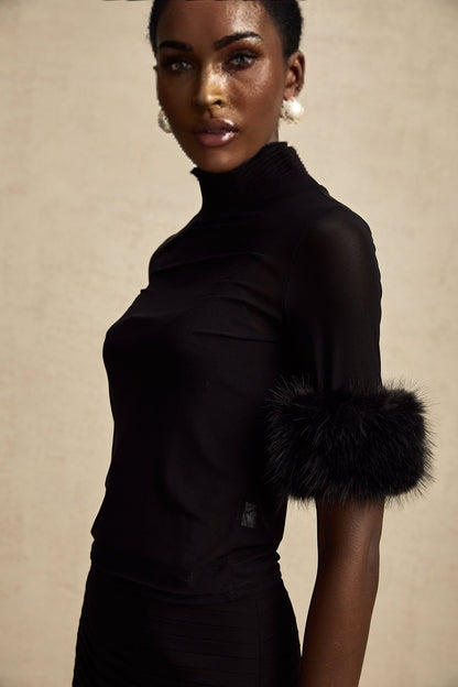 Woman wearing black sleeveless top with faux fur trim and tulle overlay