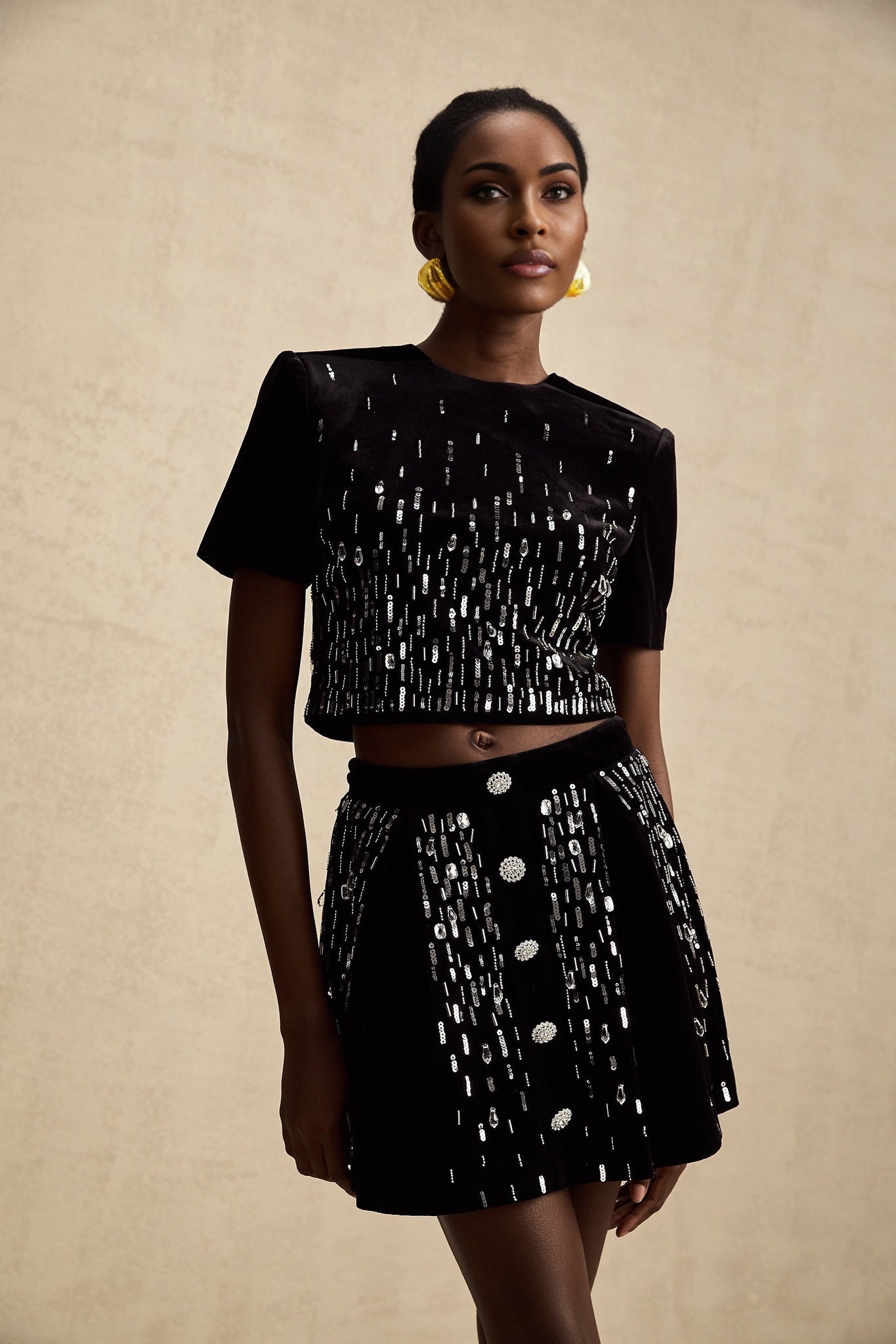 Woman wearing black velvet matching set with embellished top and skirt named Isabeau
