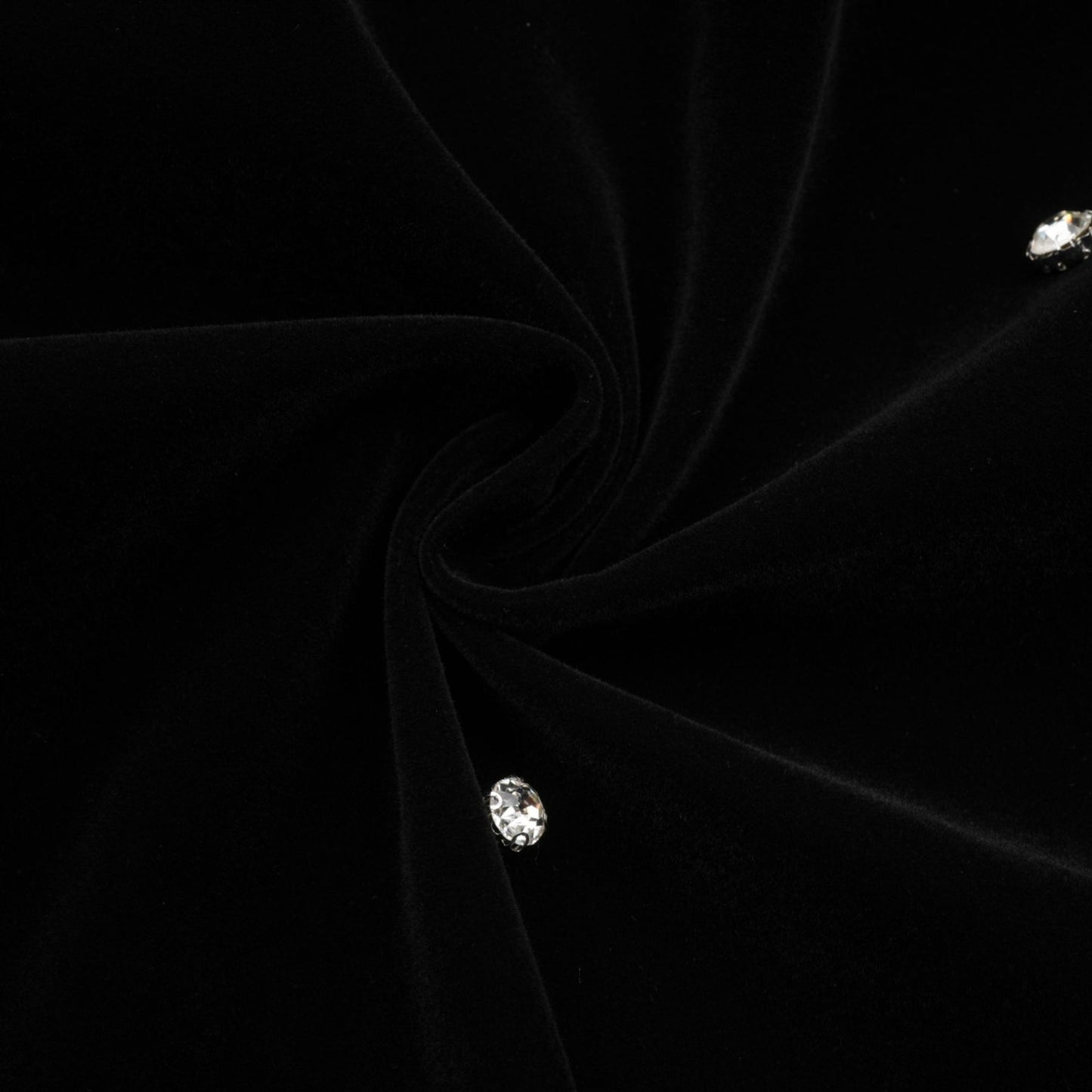 Woman wearing black velvet midi dress with embellishments form fitting silhouette sleeveless design