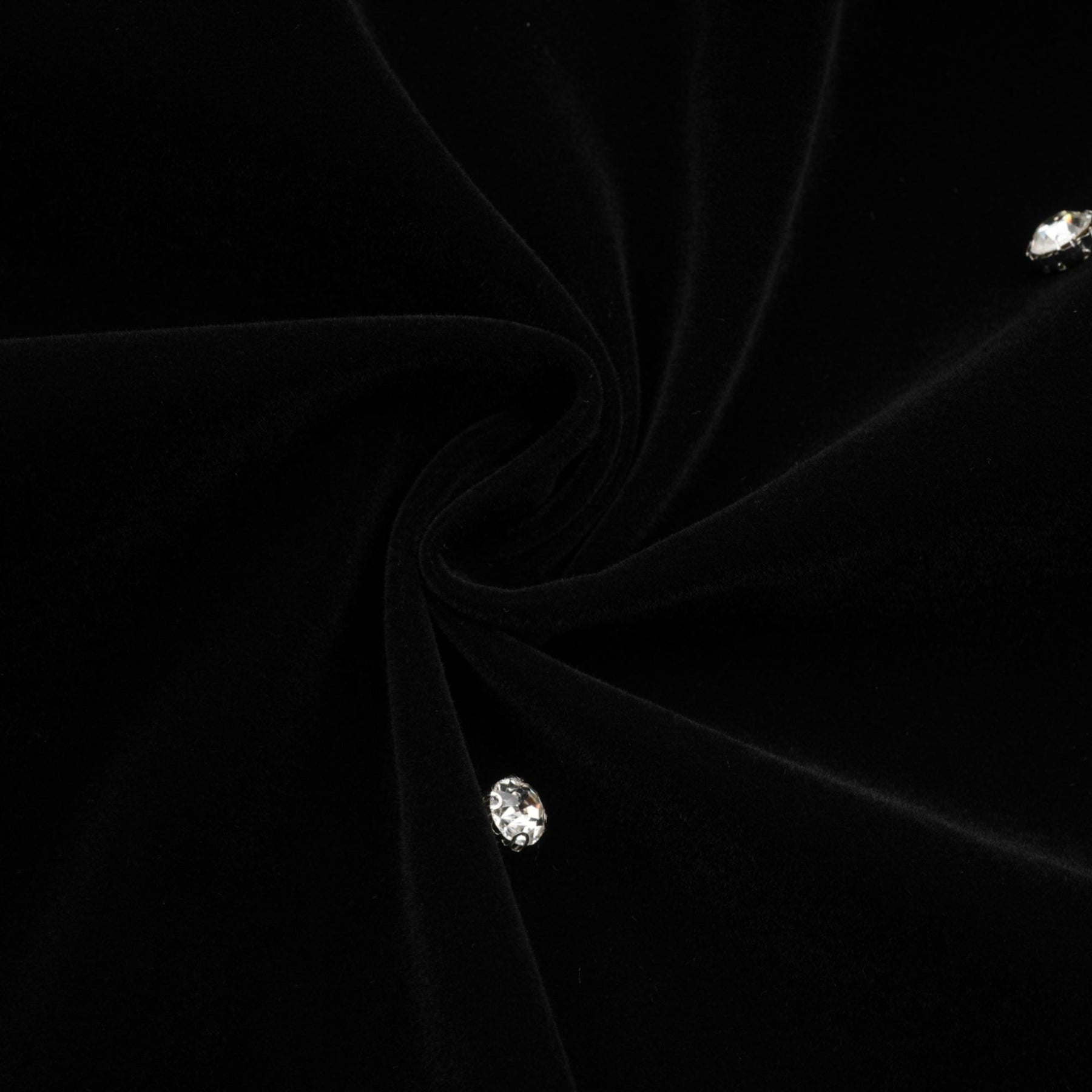 Woman wearing black velvet midi dress with embellishments form fitting silhouette sleeveless design