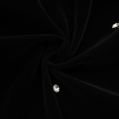 Woman wearing black velvet midi dress with embellishments form fitting silhouette sleeveless design