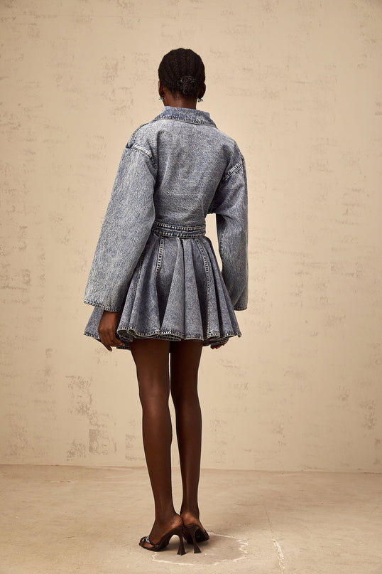 Woman wearing blue asymmetrical cropped denim jacket with distressed details and open front