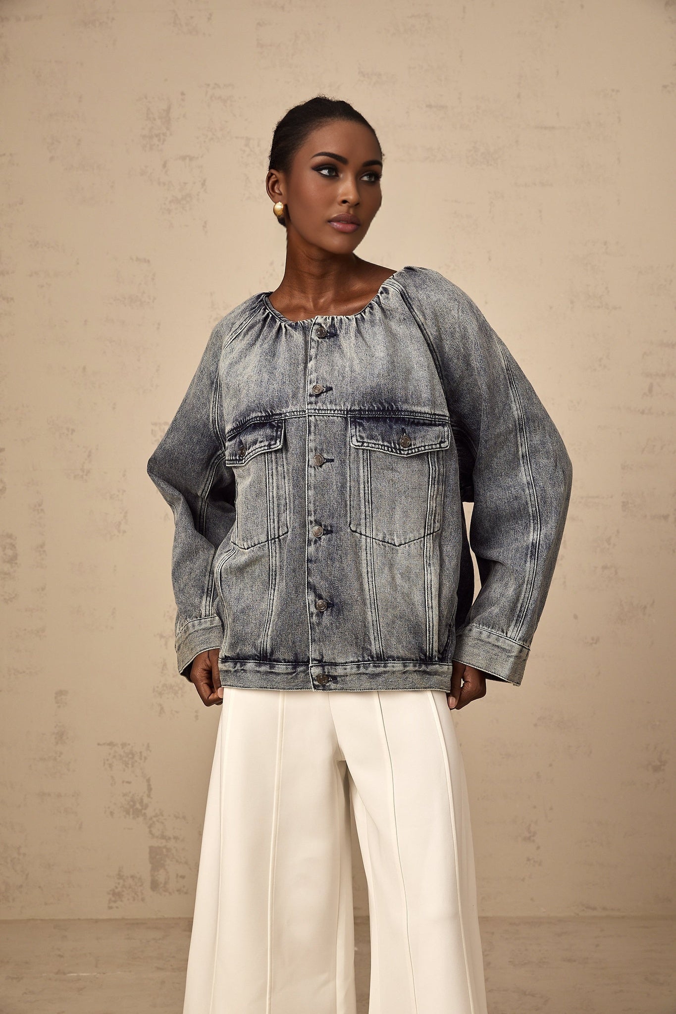 Woman wearing blue collarless denim jacket with front pockets and button closure
