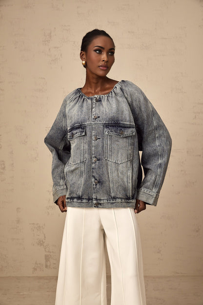 Woman wearing blue collarless denim jacket with front pockets and button closure