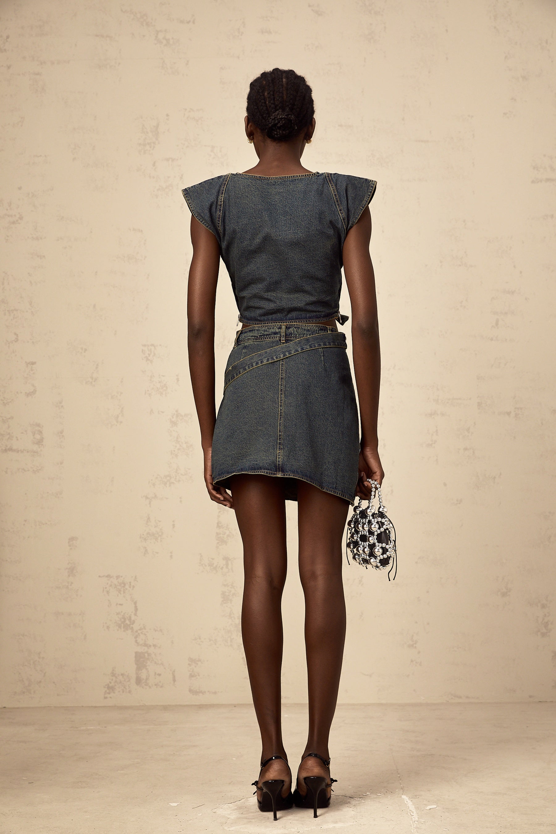 Woman wearing blue denim crop top with crossover front and matching high waisted skirt set