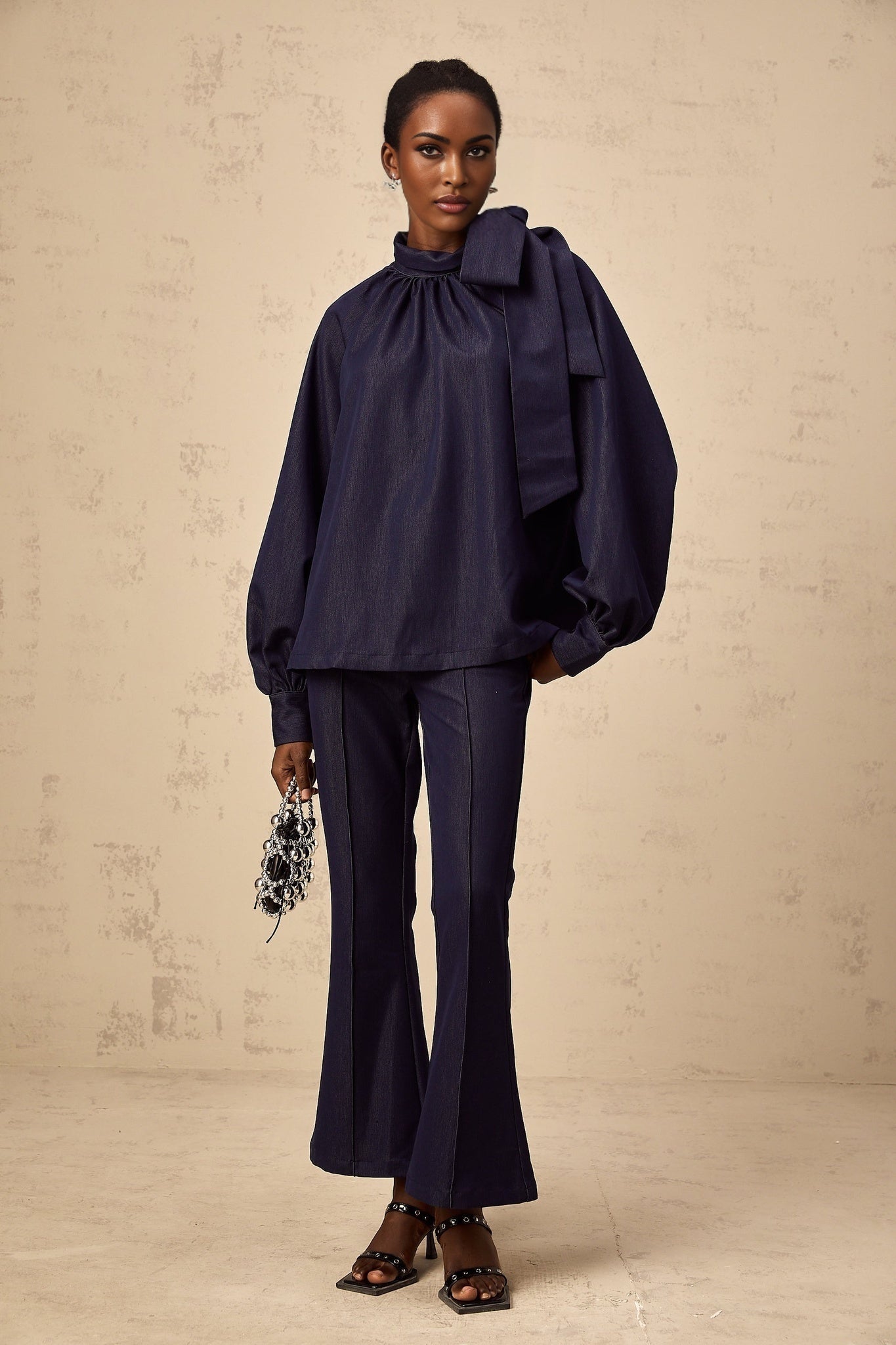 Woman wearing blue denim matching set with flared blouse and trousers named Mathilde