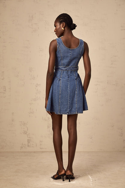 Woman wearing blue denim mini dress with belt cinched at waist