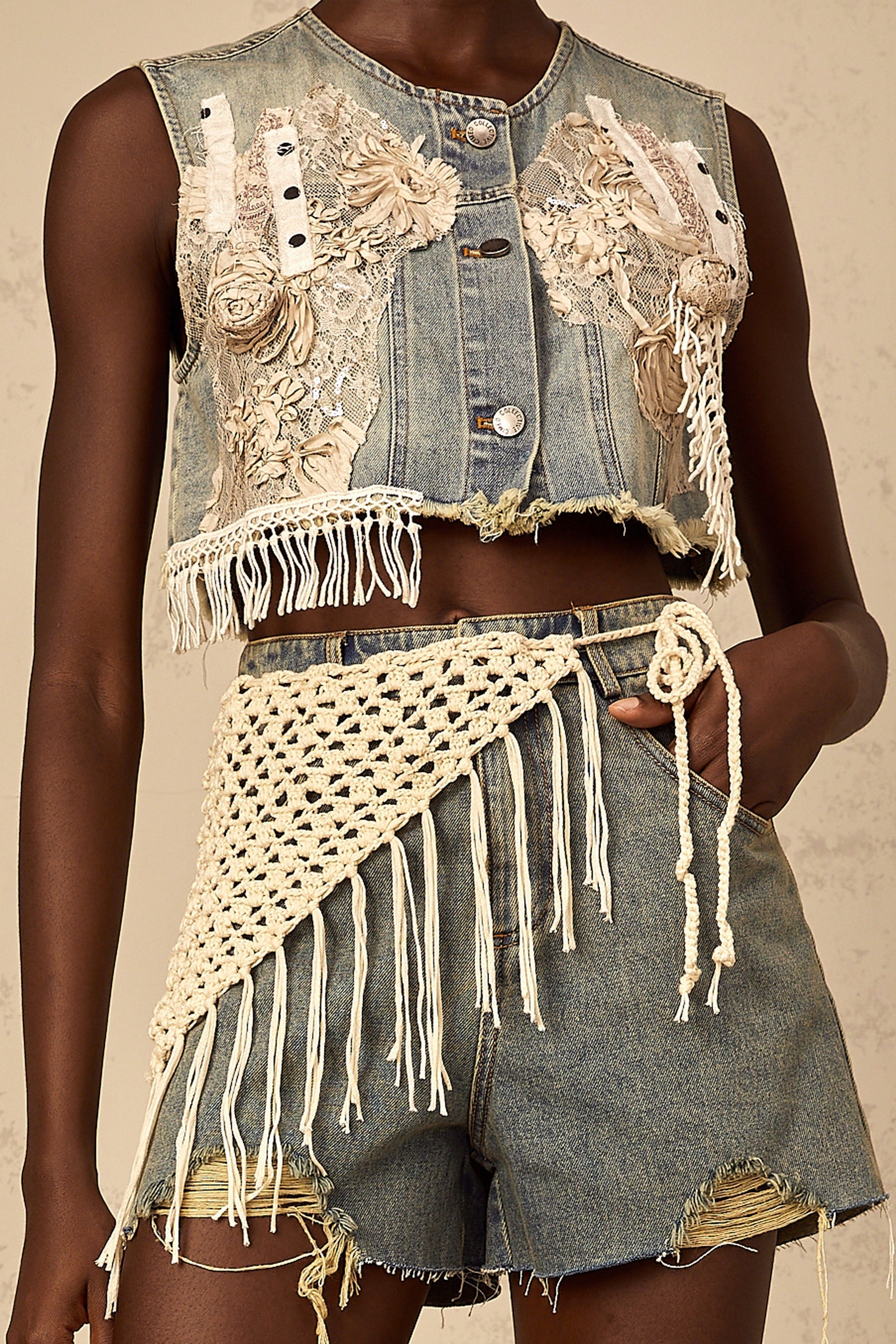 Woman wearing blue denim shorts with boho style details and embroidery standing against a plain background