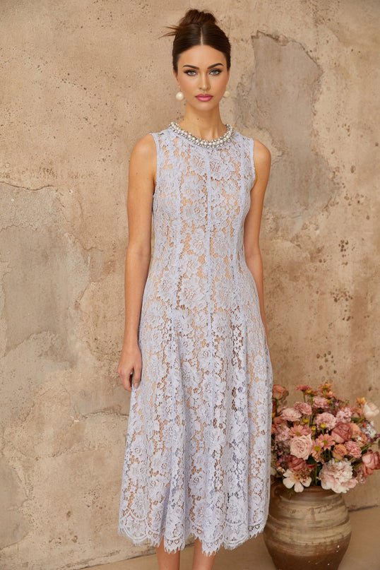 Woman wearing blue floral lace midi dress with embellishments standing in neutral background