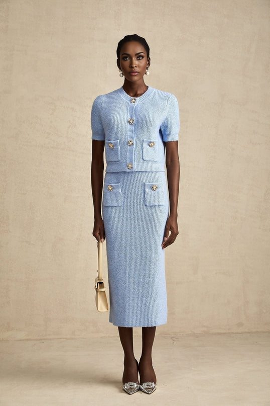 Woman wearing blue knit blouse and matching skirt set called Chantal outfit standing against plain background