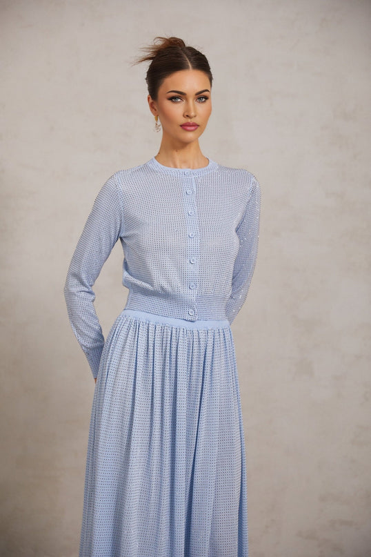 Woman wearing blue knitted two piece outfit with rhinestone details top has short sleeves skirt is knee length set sparkles in light