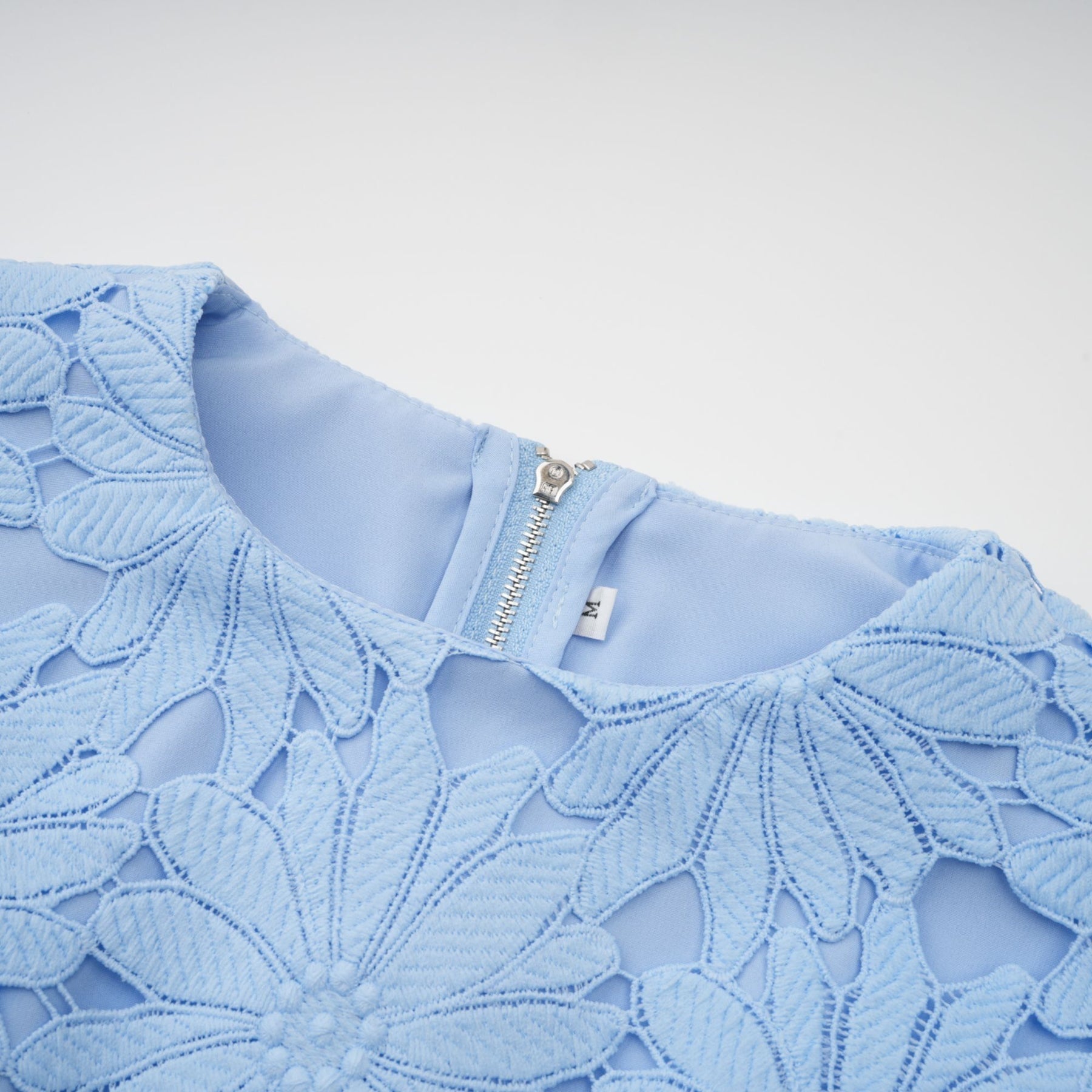 Woman wearing blue lace top and matching skirt set with floral pattern and scalloped edges