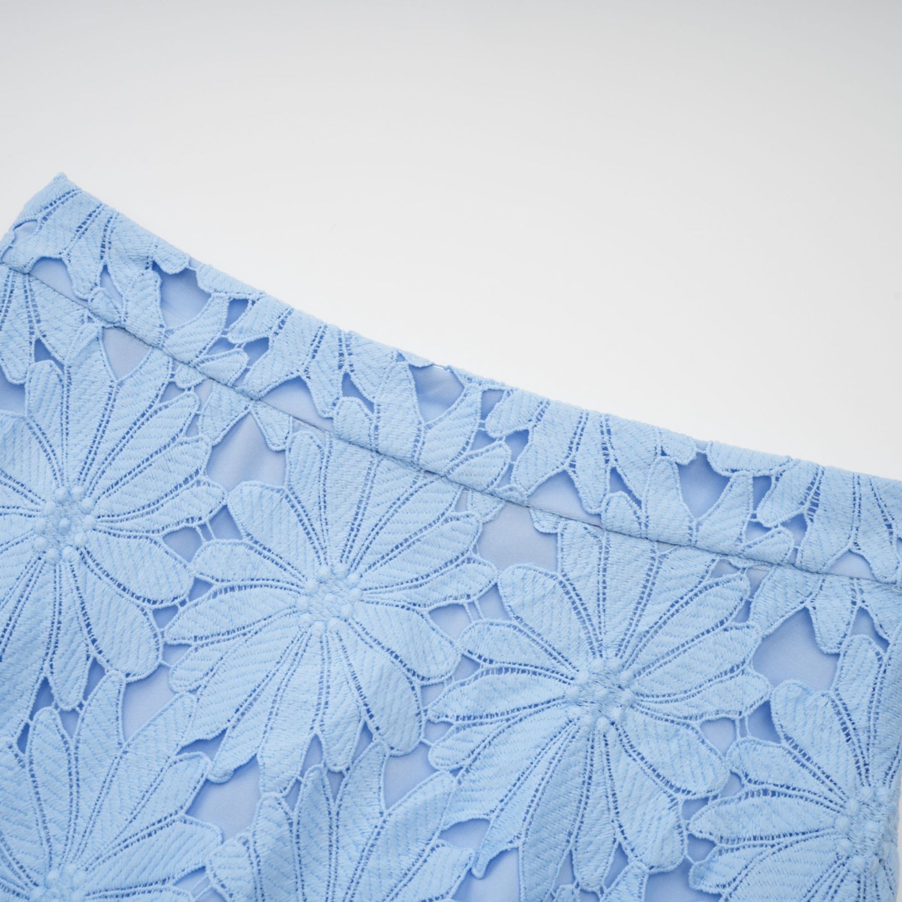 Woman wearing blue lace top and matching skirt set with floral pattern and scalloped edges