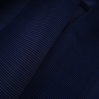 Woman wearing blue patterned cape and matching skirt set with creased fabric design