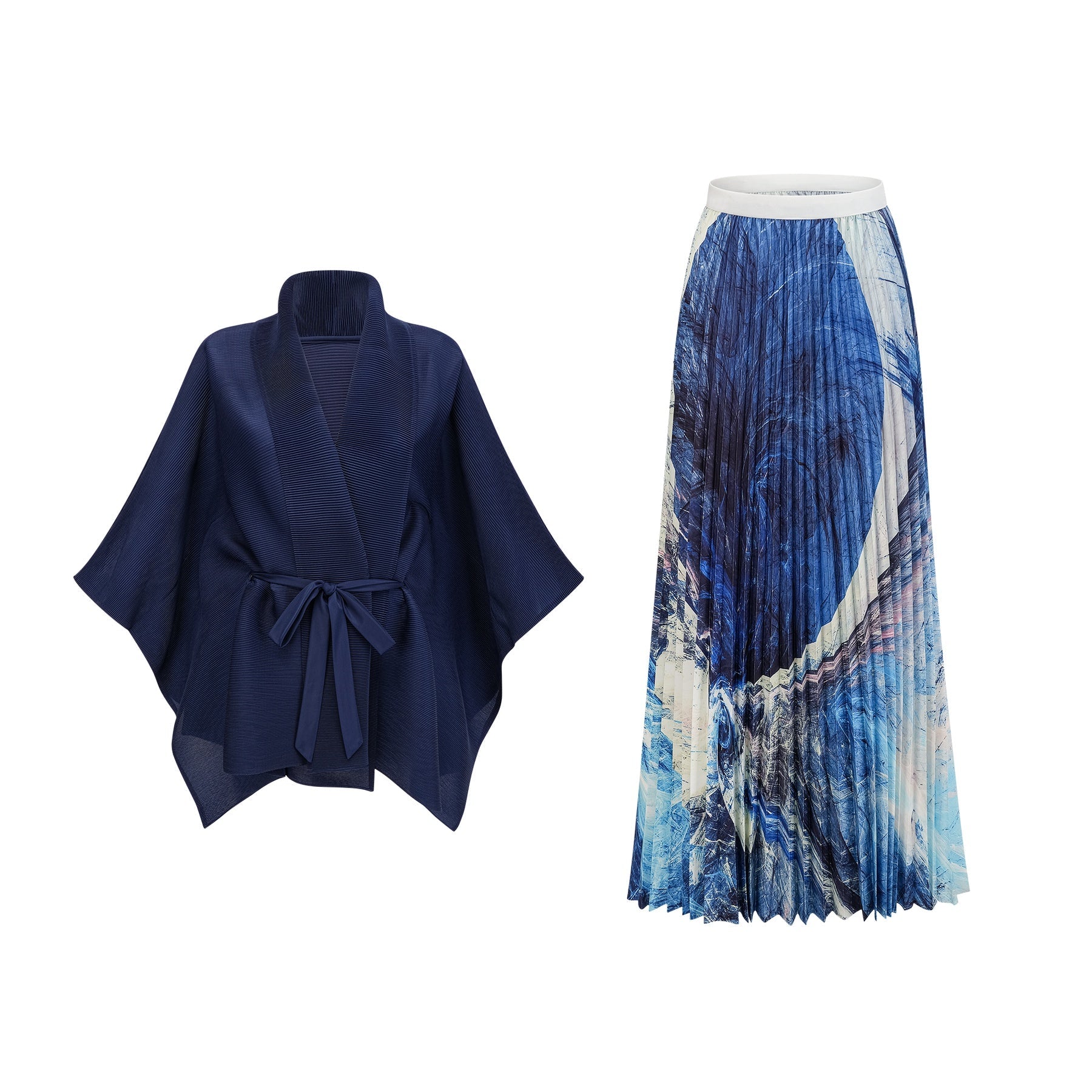 Woman wearing blue patterned cape and matching skirt set with creased texture standing against plain background