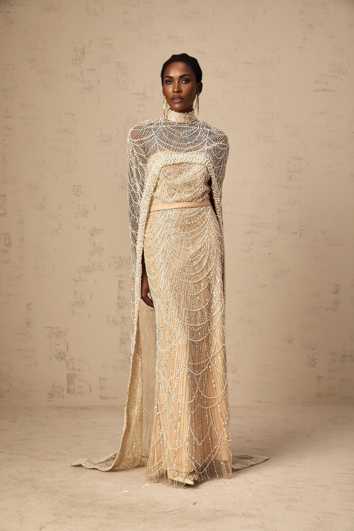 Woman wearing champagne colored beaded gown with matching cape elegant formal attire full length view