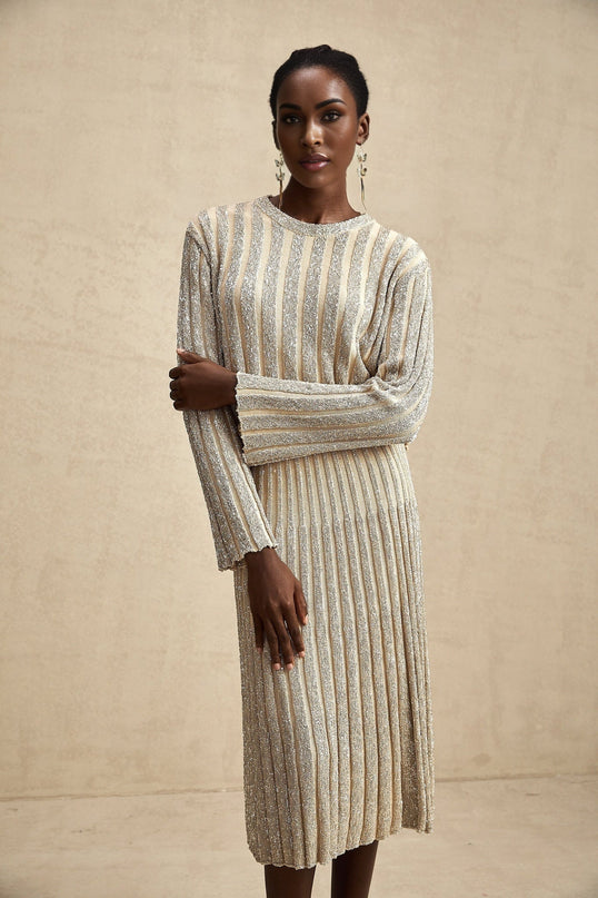 Woman wearing champagne colored knit top and skirt set with vertical stripes matching pattern on both pieces