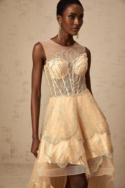Woman wearing champagne colored sleeveless gown with embellished bodice and high low skirt with floral daisy pattern