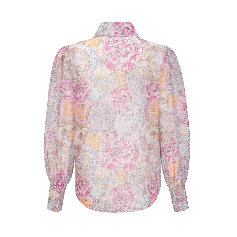 Woman wearing cherry pink matching set with patterned shirt and skirt standing against plain background