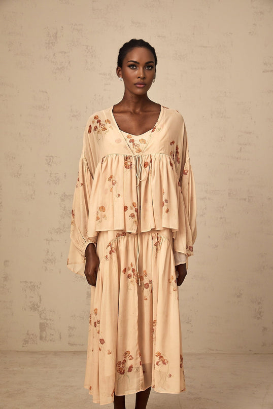 Woman wearing coralpink floral print matching blouse and dress set Blouse has pleated details Dress is sleeveless with a flowy skirt