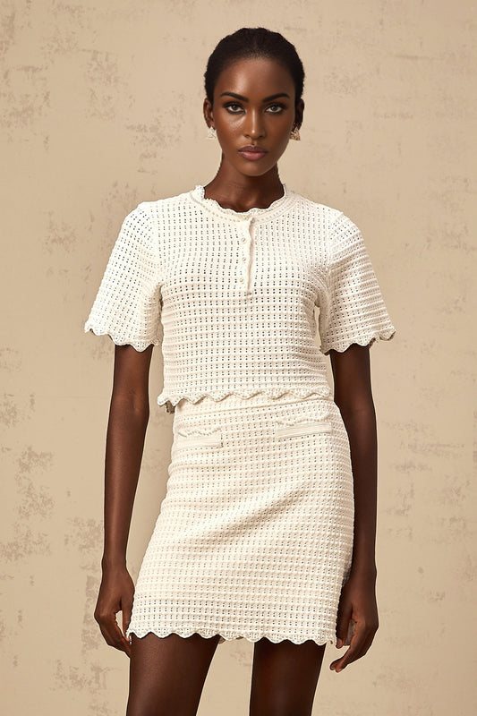 Woman wearing creamwhite matching set with ruffled top and skirt in pointelle knit fabric