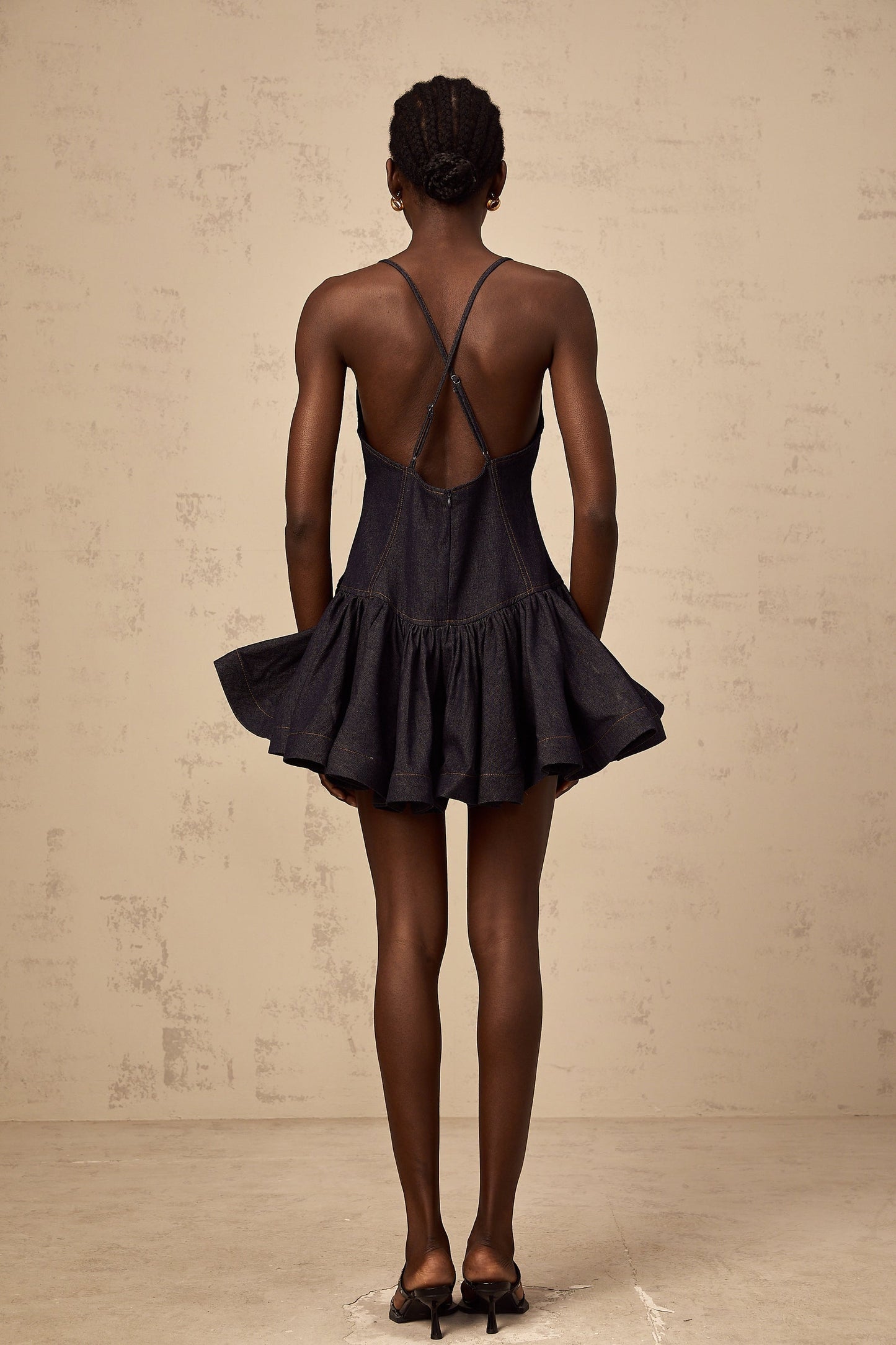 Woman wearing dark blue denim mini dress with flounce detail