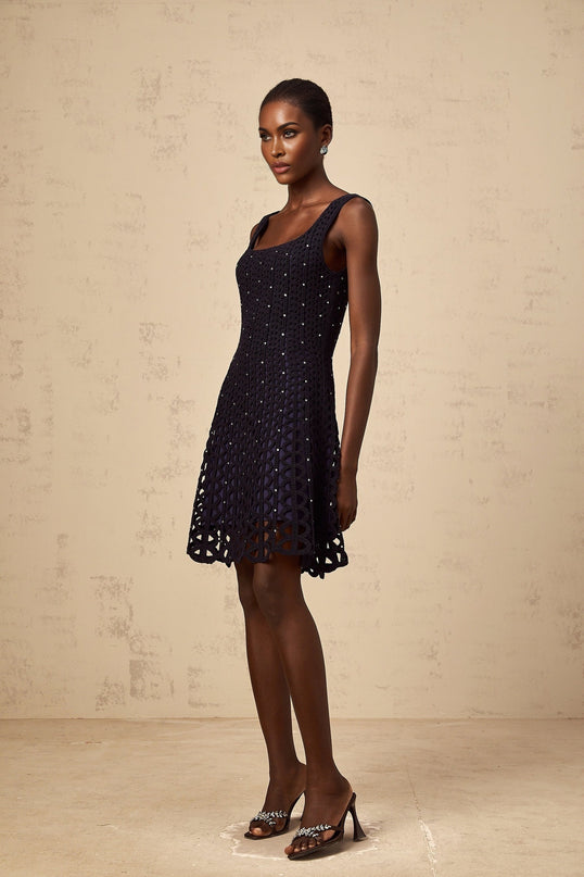 Woman wearing dark blue mini dress with crochet knit pattern and embellished cutout details