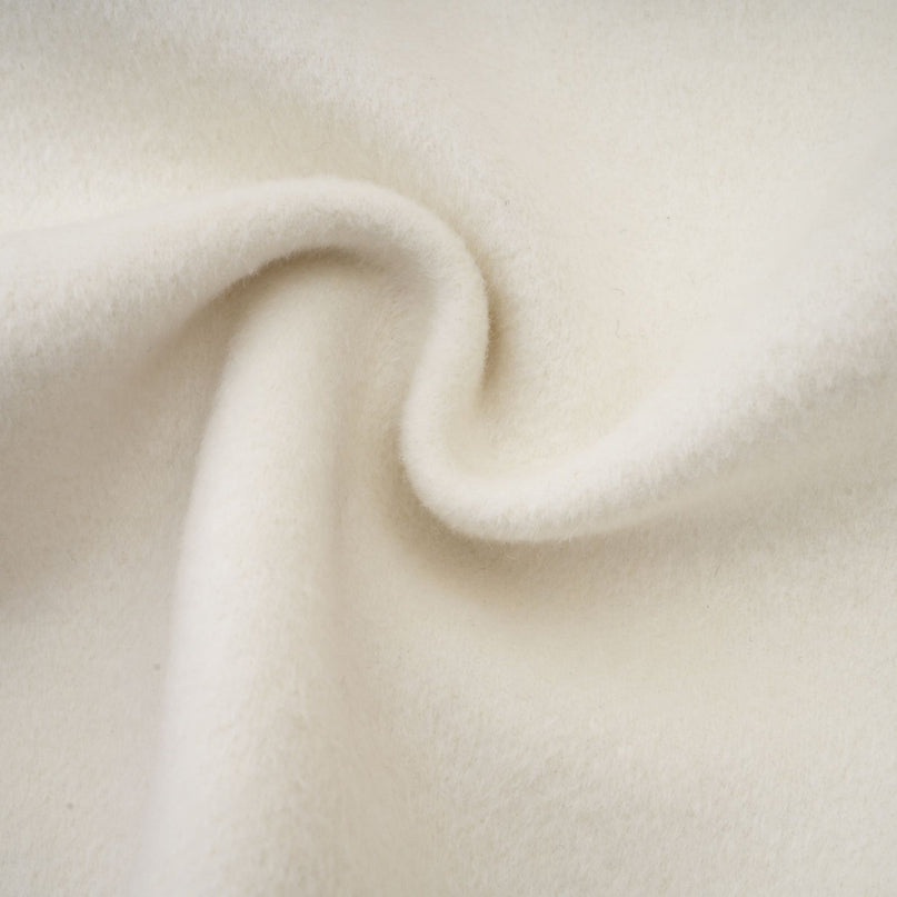 Woman wearing elegant white jacket with cape design and embellished details