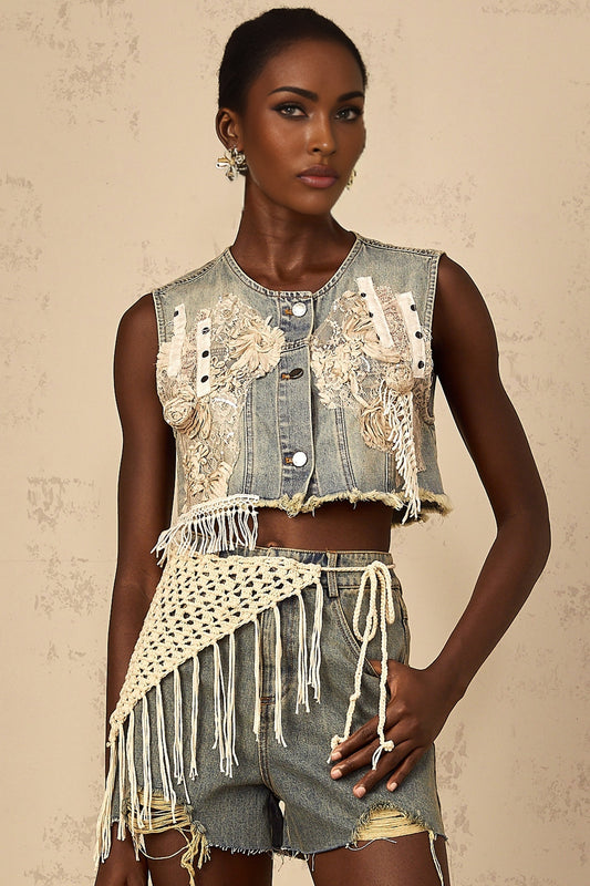 Woman wearing faded blue denim shorts with bohemian style embroidery and distressed details