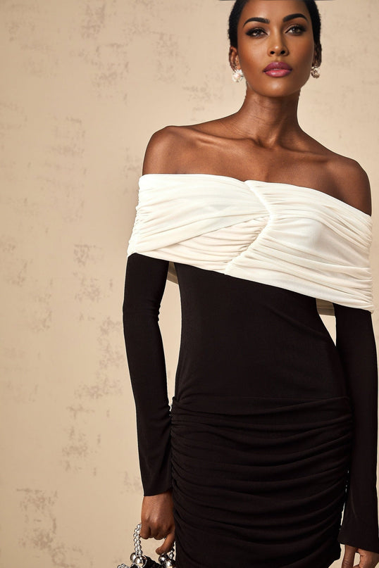 Woman wearing fitted mini dress with color blocking and ruched details in contrasting colors