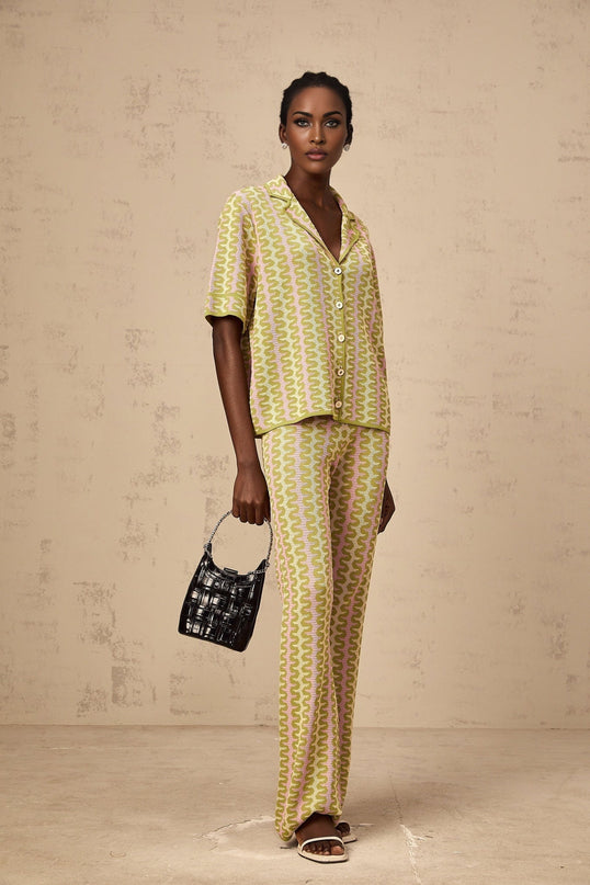 Woman wearing green colorblock knitted shirt and matching trousers standing in relaxed pose