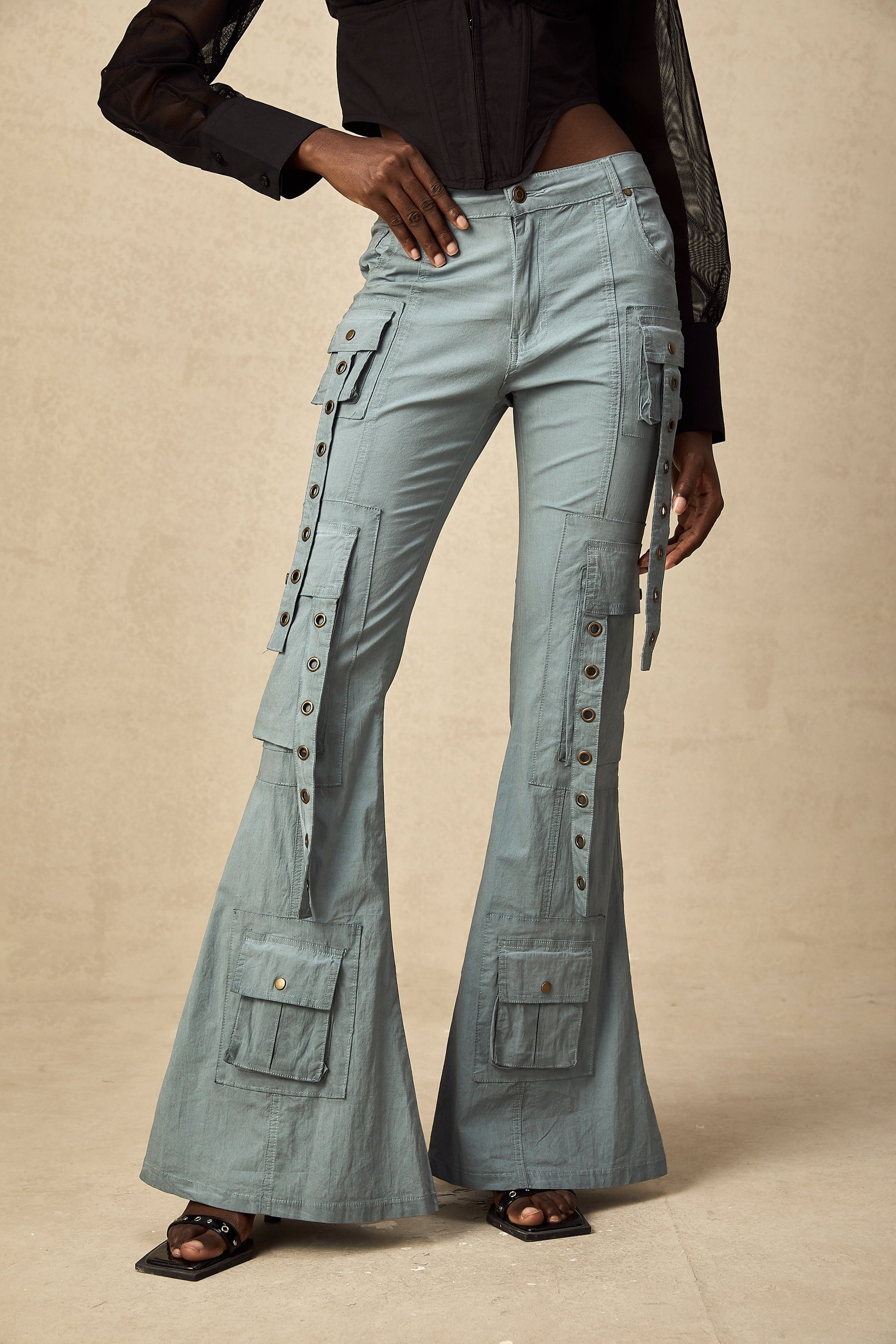 Woman wearing green flared cargo trousers with belt loops and multiple pockets standing in casual pose