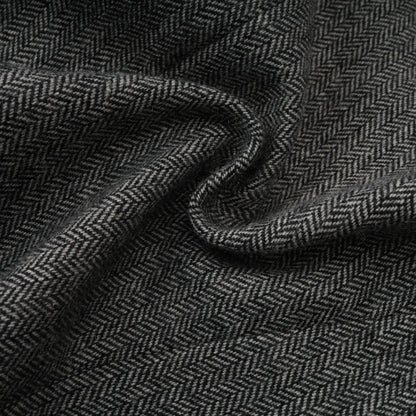 Woman wearing grey herringbone pattern matching set with top and shorts standing against plain background