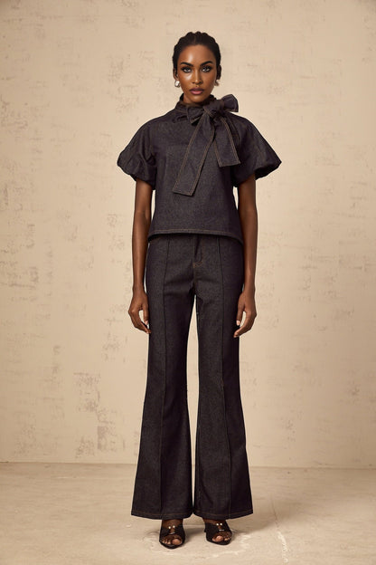 Woman wearing indigo blue denim blouse and jeans set with contrasting white stitching visible on both pieces