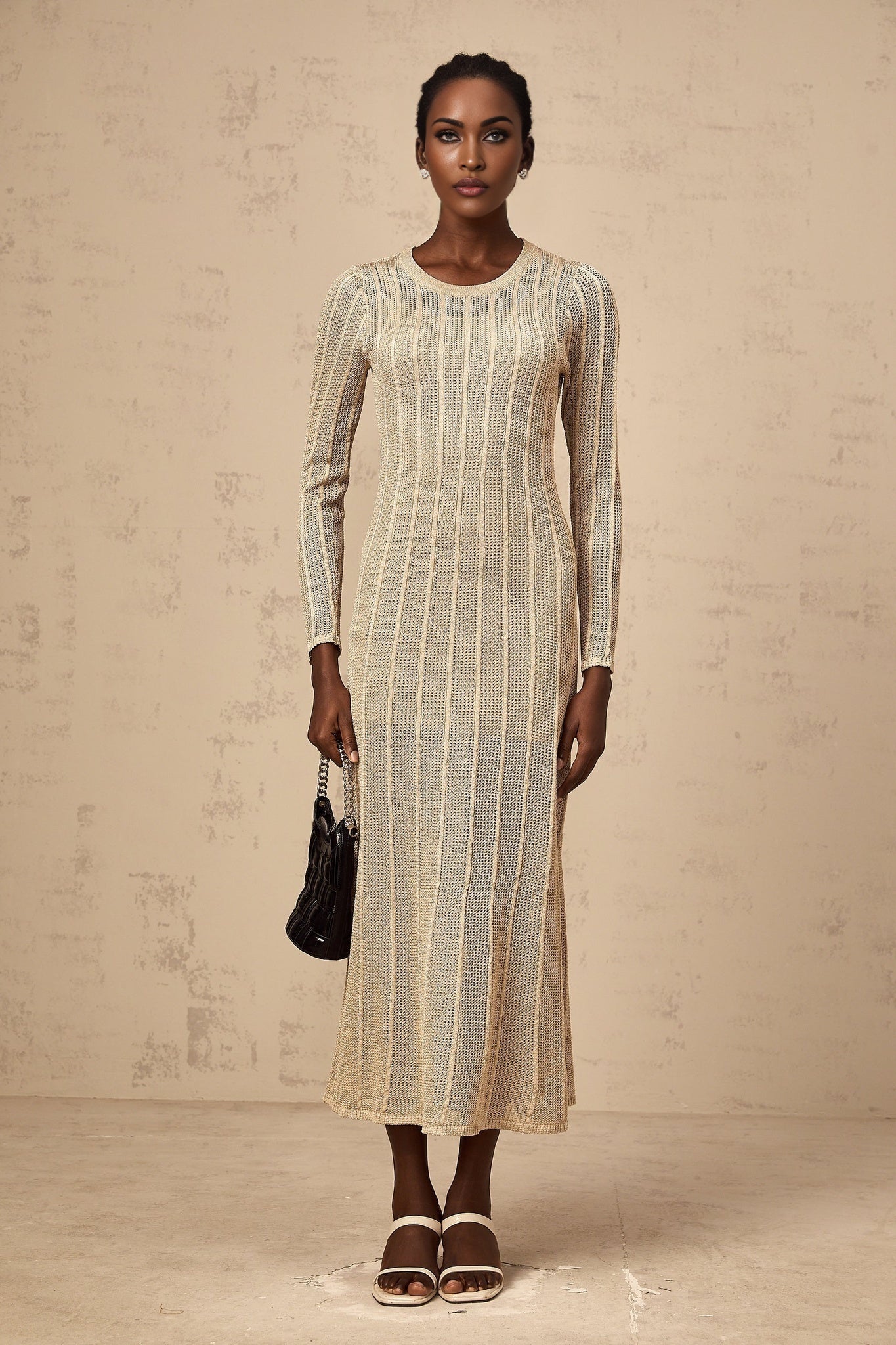 Woman wearing khaki colored fitted knit midi dress with long sleeves and ribbed texture standing against plain background