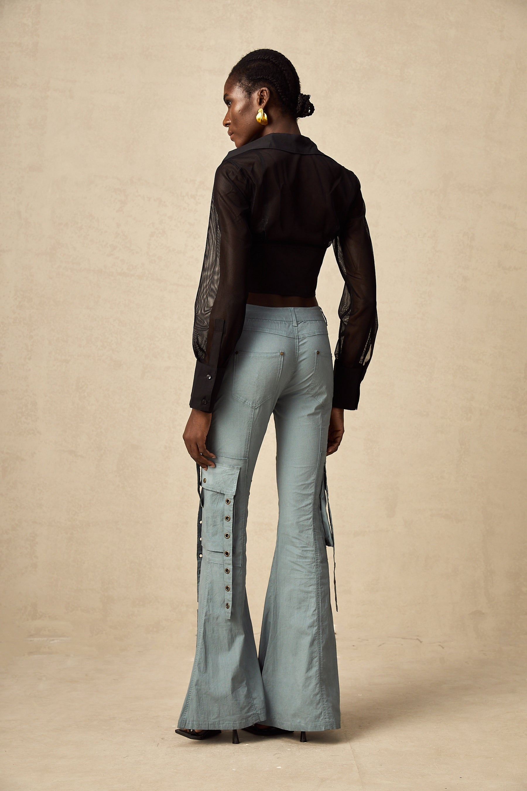 Woman wearing khaki flared cargo trousers with belt loops and multiple pockets standing in relaxed pose