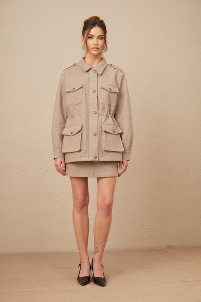 Woman wearing khaki wool twill jacket and matching culottes standing against plain background