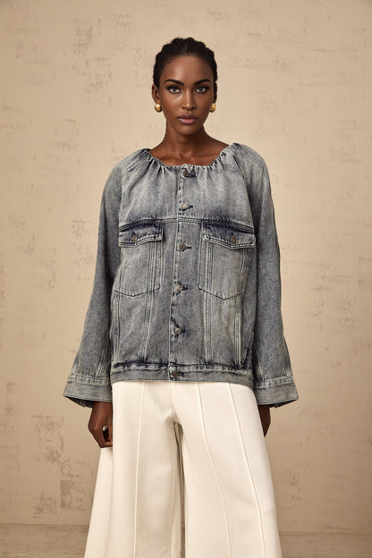Woman wearing light blue collarless denim jacket with button front closure and chest pockets