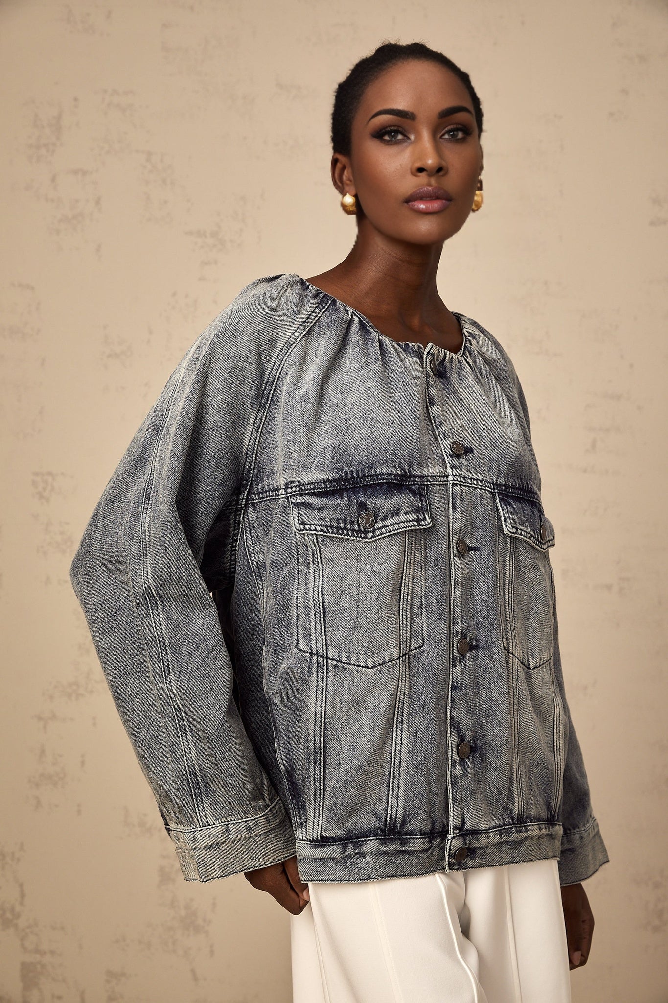 Woman wearing light blue collarless denim jacket with button front closure and chest pockets