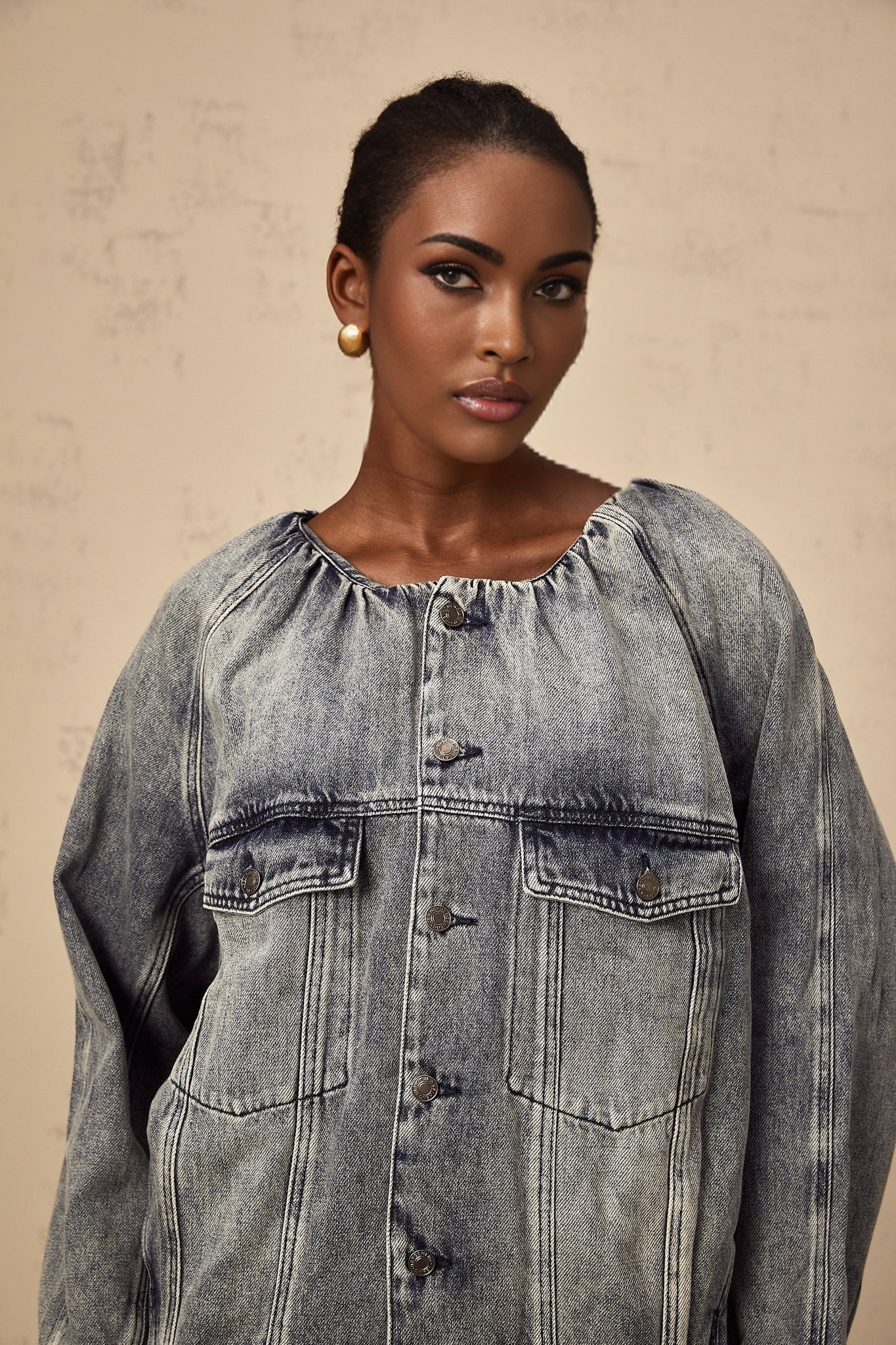 Woman wearing light blue collarless denim jacket with buttoned front and patch pockets