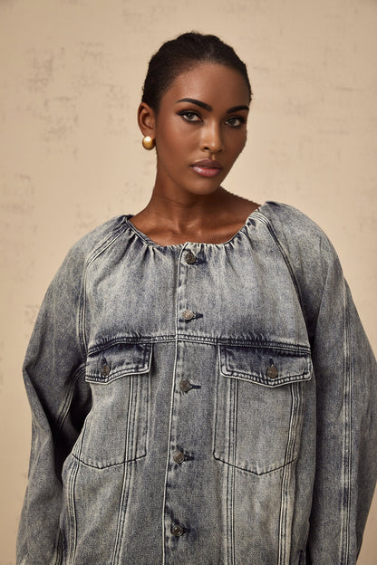 Woman wearing light blue collarless denim jacket with buttoned front and patch pockets