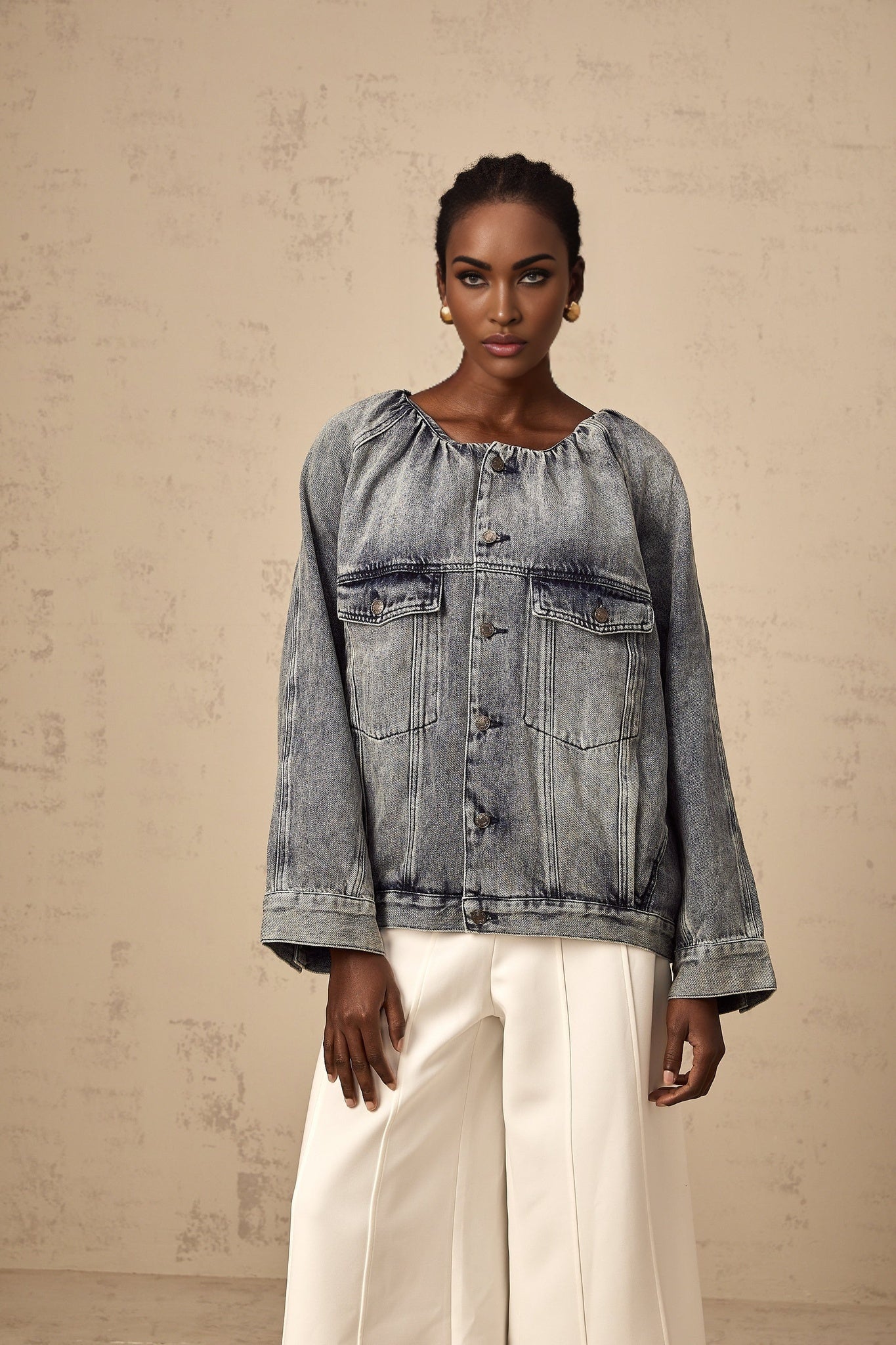 Woman wearing light blue collarless denim jacket with front pockets and button closure