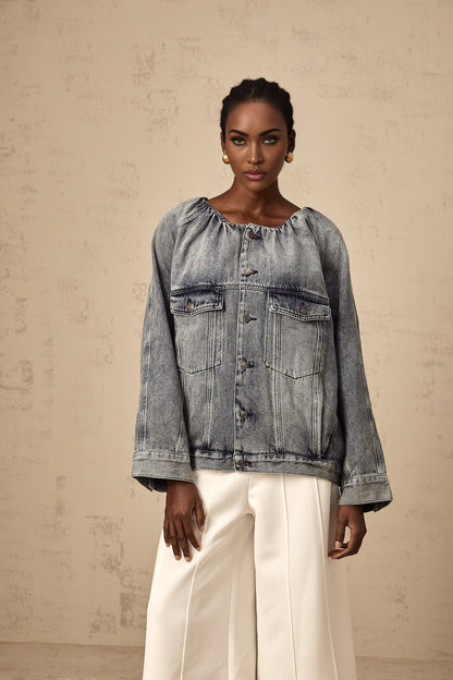Woman wearing light blue collarless denim jacket with front pockets and button closure