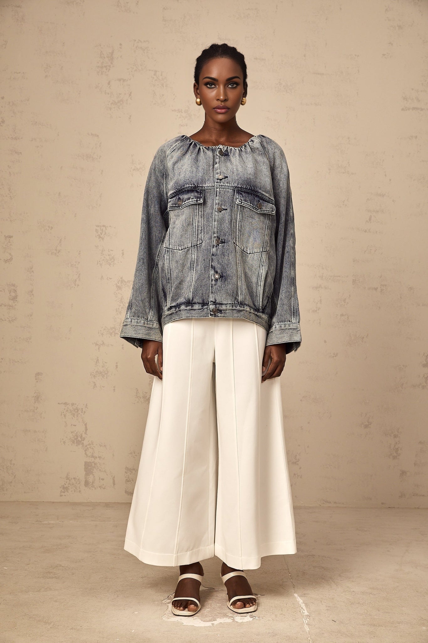 Woman wearing light blue collarless denim jacket with front pockets and button closure