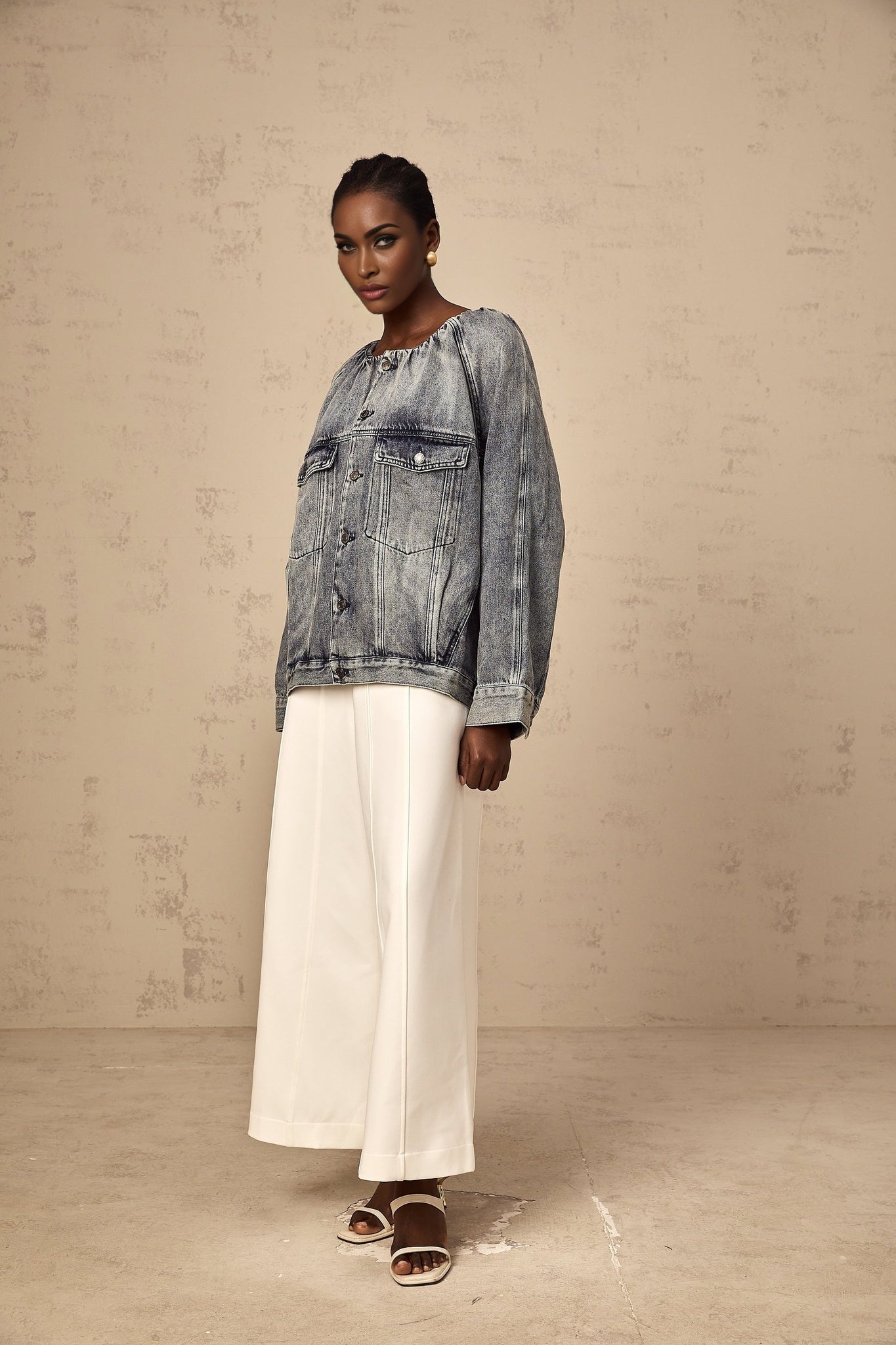 Woman wearing light blue collarless denim jacket with front pockets and button closure