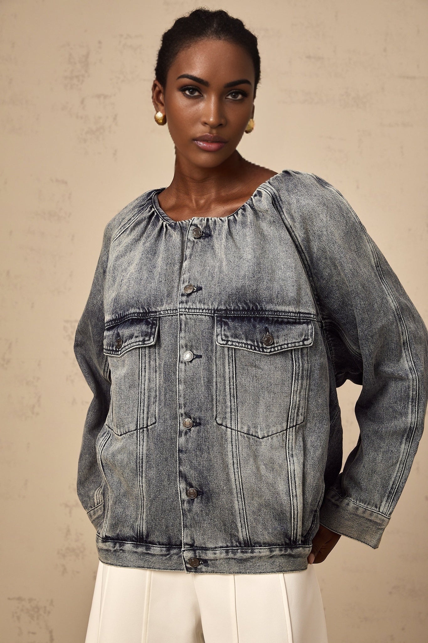 Woman wearing light blue collarless denim jacket with front pockets and button closure