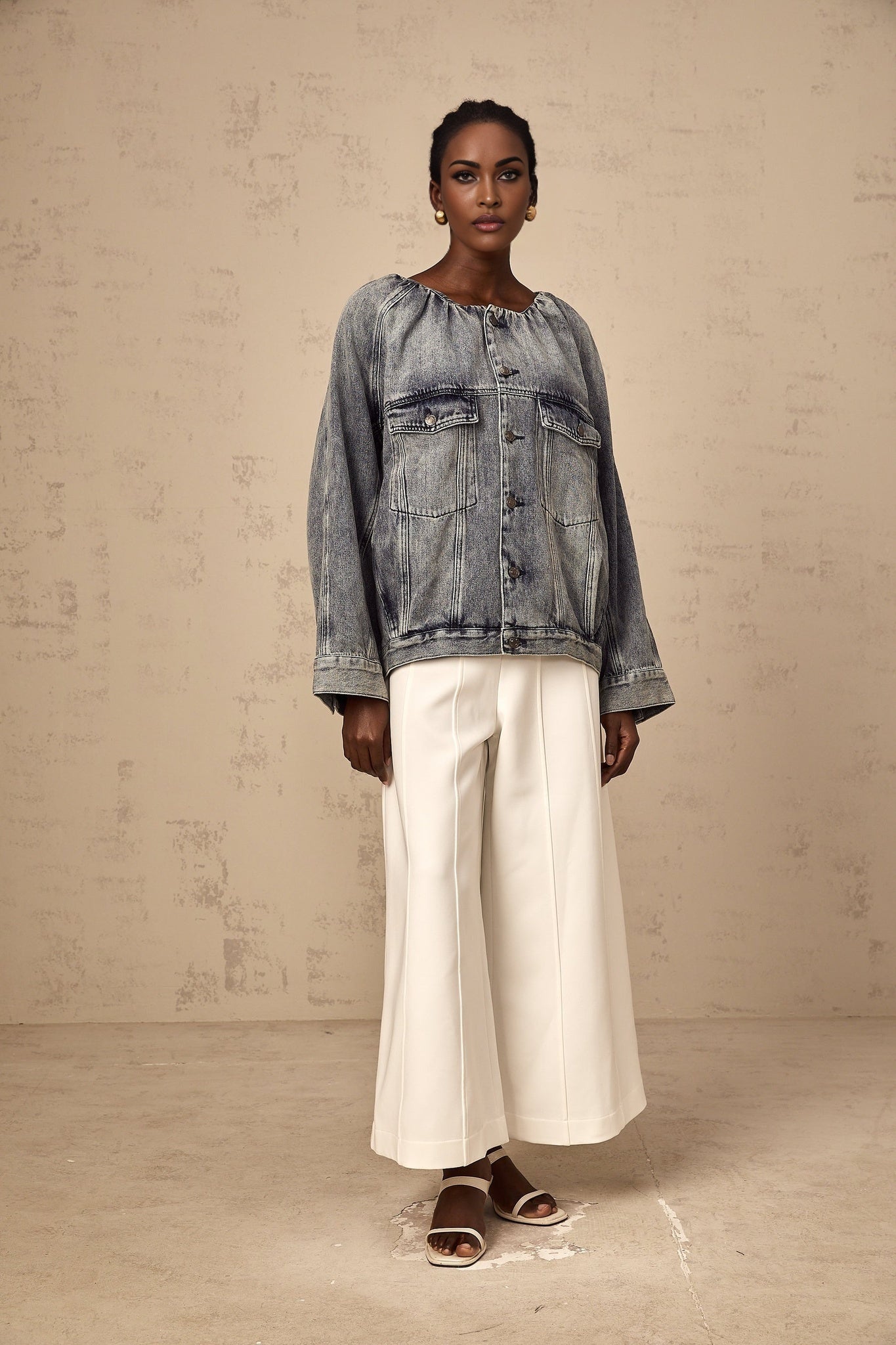 Woman wearing light blue collarless denim jacket with front pockets and button closure